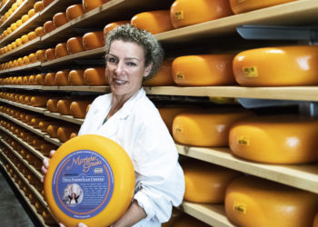 woman standing in front of rows of cheese