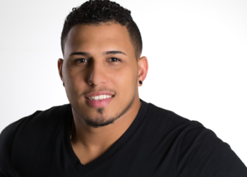 headshot of a broad-shouldered man wearing a black T shirt