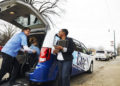 Black woman looking at a patient being loaded into a van