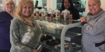 three white women and one Black woman stand around a counter
