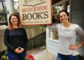 two women next to a bookstore sign