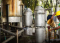 men gathered around large silver tanks