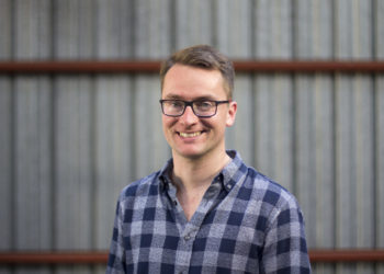white man smiling in front of a wall