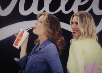 Two white women in profile with bright red lipstick