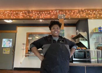 Black woman standing confidently in an apron