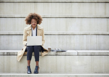 woman sitting alone on concrete steps, open computer on her lap